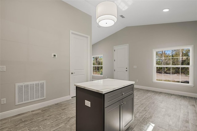 kitchen featuring a center island, lofted ceiling, visible vents, light wood-style floors, and baseboards