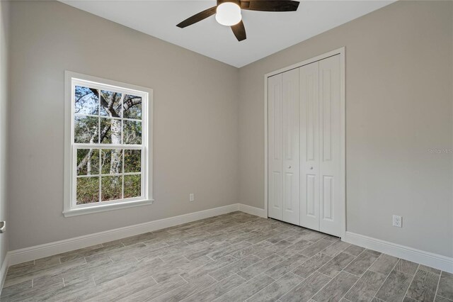 unfurnished bedroom featuring light wood-style floors, ceiling fan, baseboards, and a closet