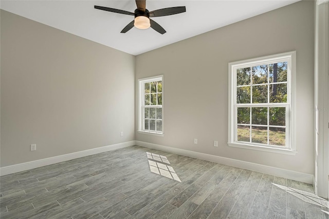 empty room featuring wood finished floors, a ceiling fan, and baseboards