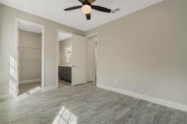 unfurnished bedroom with visible vents, light wood-style flooring, baseboards, and a spacious closet