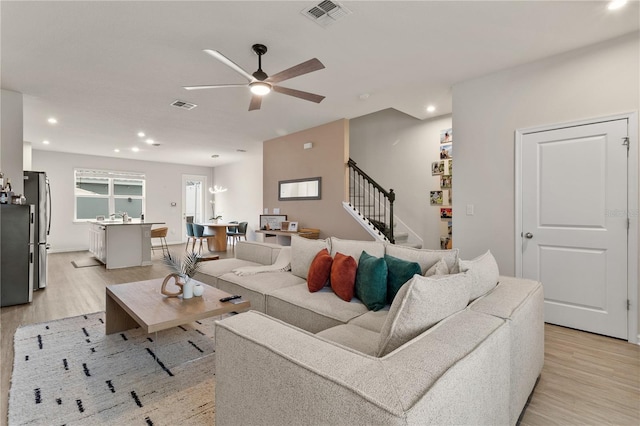 living area with stairway, light wood-style flooring, and visible vents