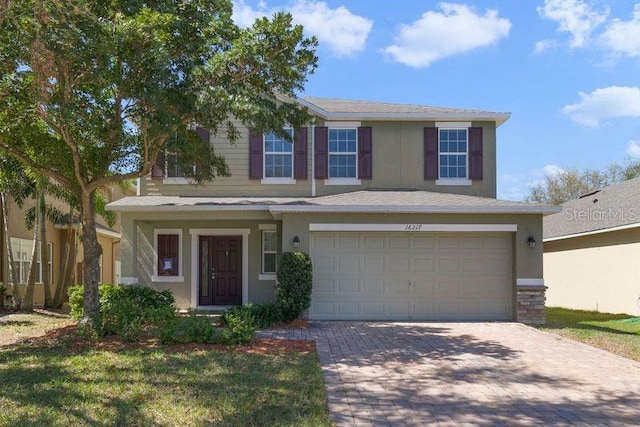 view of front facade with a garage, decorative driveway, and stucco siding