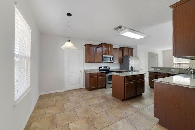 kitchen featuring visible vents, hanging light fixtures, appliances with stainless steel finishes, a sink, and a kitchen island