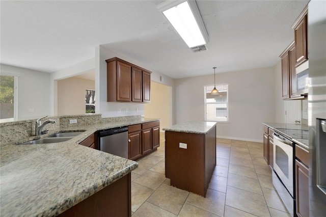 kitchen featuring appliances with stainless steel finishes, a kitchen island, a sink, and a healthy amount of sunlight