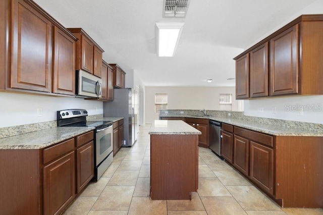 kitchen with a peninsula, a kitchen island, a sink, visible vents, and appliances with stainless steel finishes