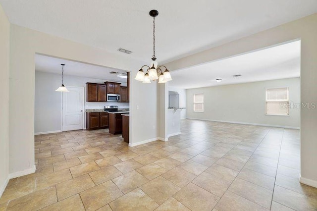 kitchen featuring stainless steel microwave, open floor plan, decorative light fixtures, light countertops, and dark brown cabinets