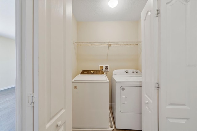 clothes washing area featuring laundry area, baseboards, a textured ceiling, and independent washer and dryer