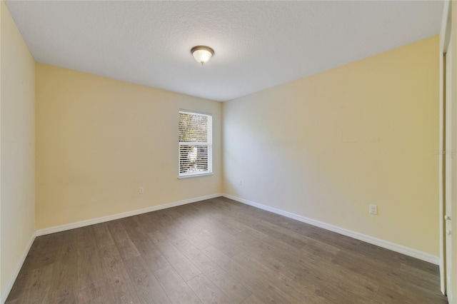 empty room featuring a textured ceiling, baseboards, and wood finished floors