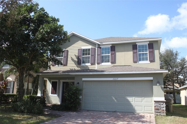 traditional-style house with a garage, decorative driveway, and stucco siding