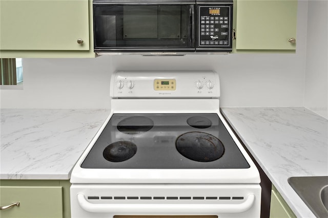 kitchen with black microwave, green cabinets, and white electric range