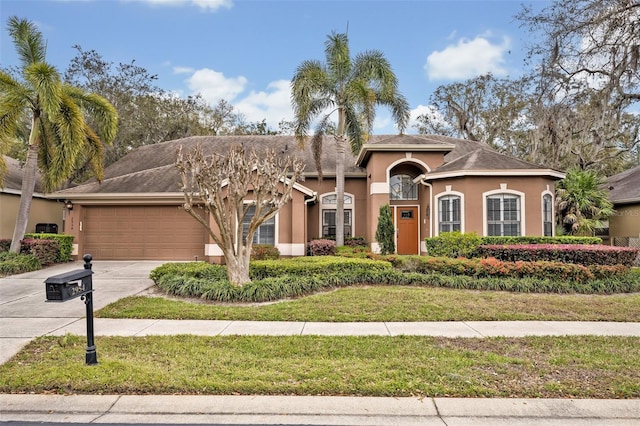 mediterranean / spanish-style house with an attached garage, driveway, and stucco siding