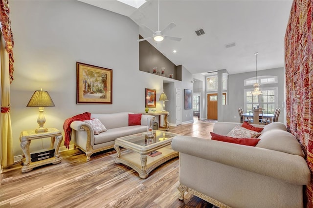 living room with high vaulted ceiling, light wood-type flooring, visible vents, and a ceiling fan