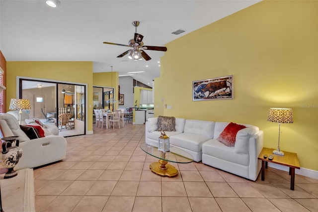 living room with light tile patterned floors, visible vents, ceiling fan, vaulted ceiling, and baseboards