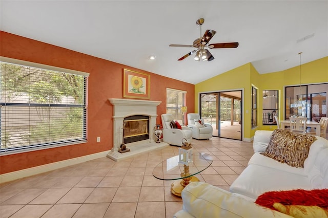 living area with light tile patterned floors, lofted ceiling, visible vents, a glass covered fireplace, and ceiling fan