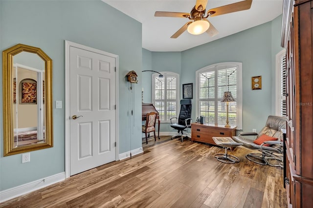 living area featuring a ceiling fan, baseboards, and wood finished floors