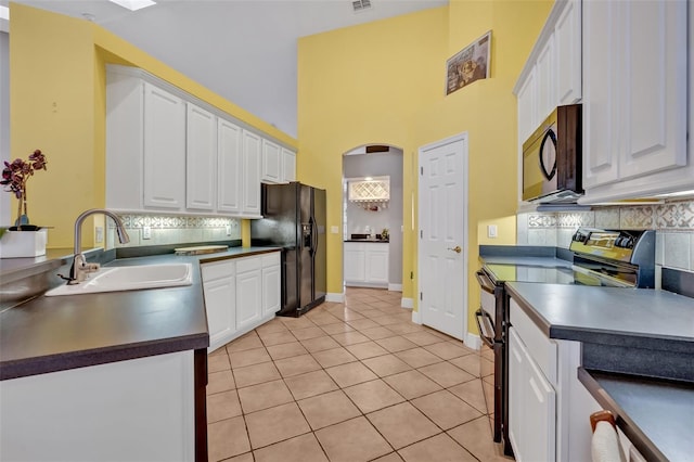 kitchen featuring light tile patterned flooring, a sink, black appliances, and white cabinetry