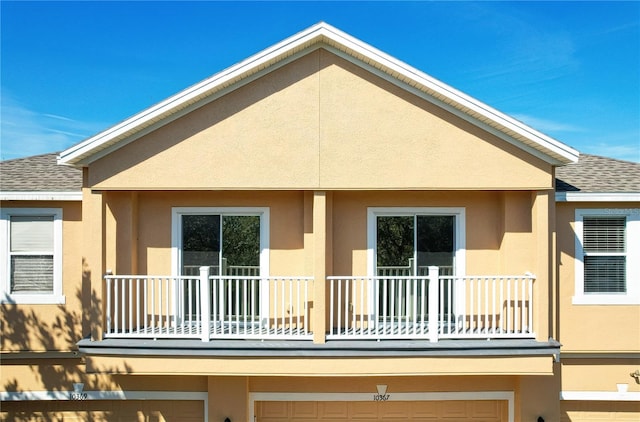 back of house featuring roof with shingles and stucco siding