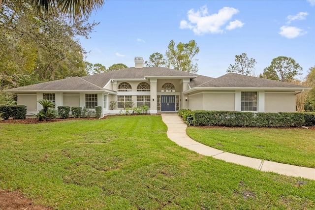 view of front of house featuring a chimney, a front lawn, and stucco siding