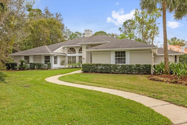 view of front of house featuring roof with shingles, a front lawn, a chimney, and stucco siding