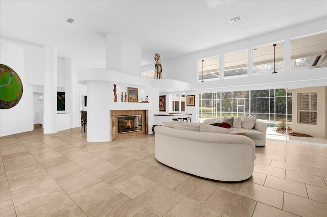 living area featuring visible vents, a fireplace, and a high ceiling