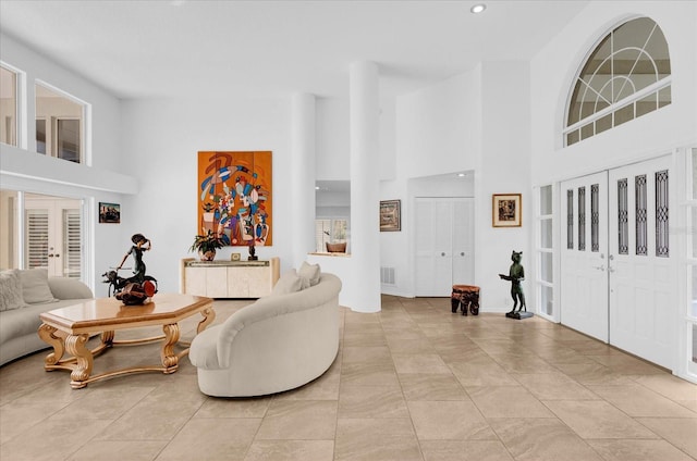 living room featuring a towering ceiling, visible vents, and french doors