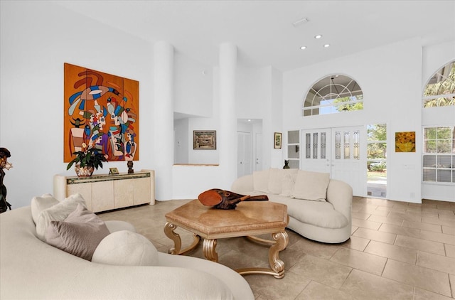 living area featuring a towering ceiling, tile patterned floors, and recessed lighting