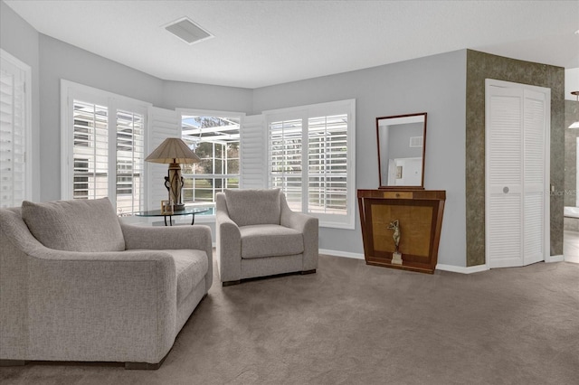 living area featuring carpet, visible vents, and baseboards