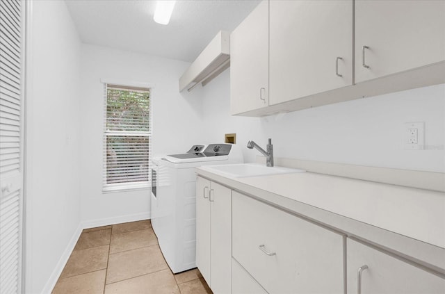 laundry area with cabinet space, light tile patterned flooring, a sink, independent washer and dryer, and baseboards