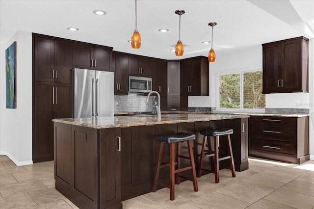 kitchen with hanging light fixtures, light stone countertops, tasteful backsplash, and appliances with stainless steel finishes