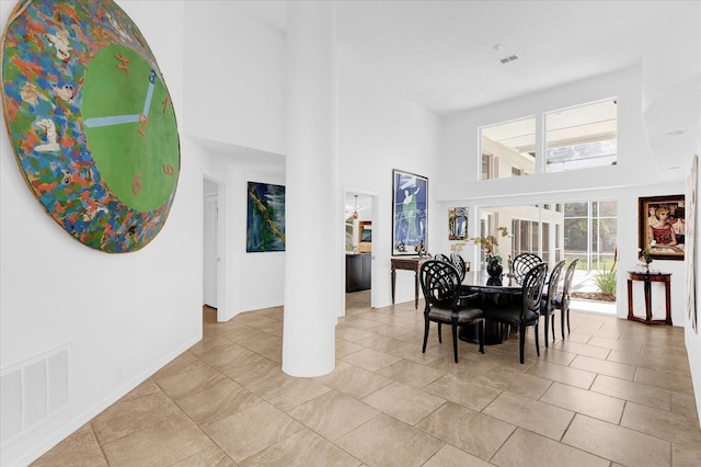 dining room featuring visible vents, a towering ceiling, baseboards, and light tile patterned flooring