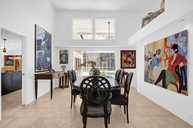 dining room featuring light tile patterned floors and a towering ceiling