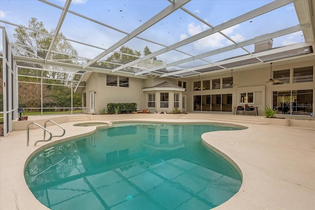 view of pool featuring a ceiling fan, a pool with connected hot tub, glass enclosure, and a patio