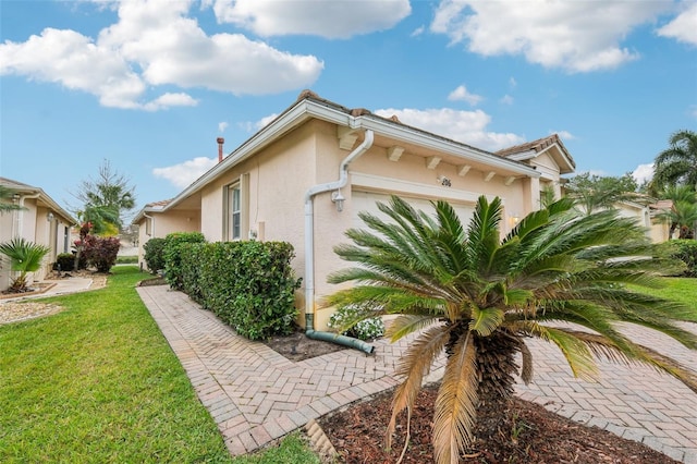 view of side of property featuring a yard, a garage, and stucco siding