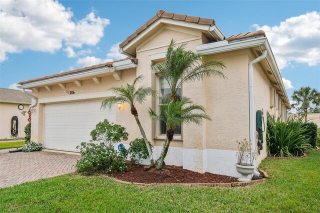 view of home's exterior with decorative driveway, an attached garage, and stucco siding