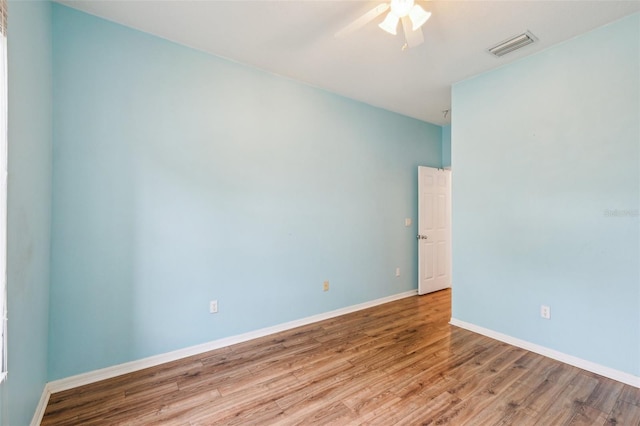 spare room with visible vents, ceiling fan, baseboards, and wood finished floors