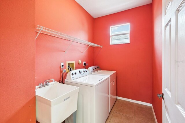 laundry room with a sink, washing machine and dryer, light tile patterned floors, baseboards, and laundry area