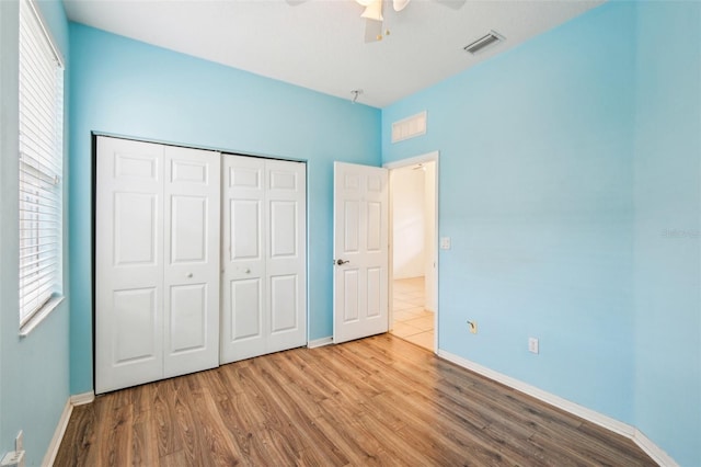 unfurnished bedroom featuring visible vents, baseboards, wood finished floors, a closet, and a ceiling fan