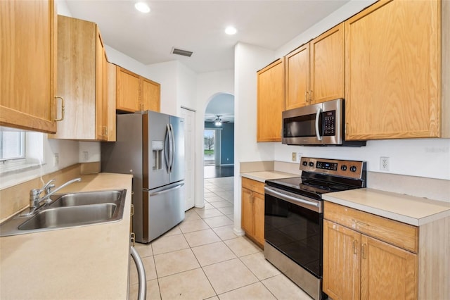 kitchen featuring visible vents, appliances with stainless steel finishes, light tile patterned flooring, arched walkways, and a sink