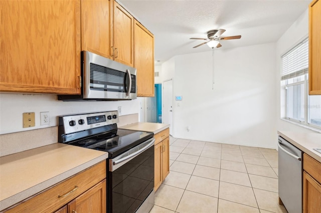 kitchen featuring ceiling fan, light countertops, light tile patterned floors, and stainless steel appliances