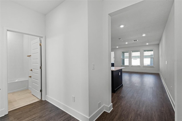 hall featuring baseboards, dark wood-type flooring, and recessed lighting