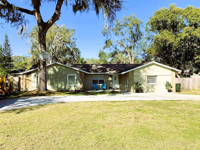 view of front facade featuring stucco siding, concrete driveway, a front yard, and fence