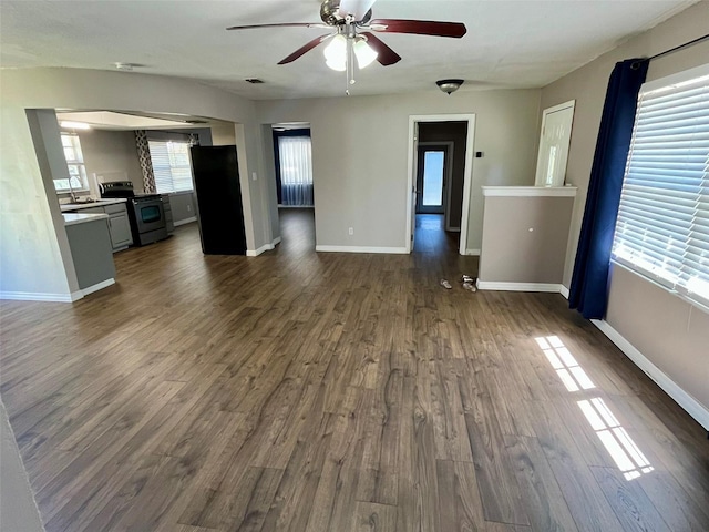 unfurnished living room featuring dark wood-type flooring, visible vents, baseboards, and ceiling fan