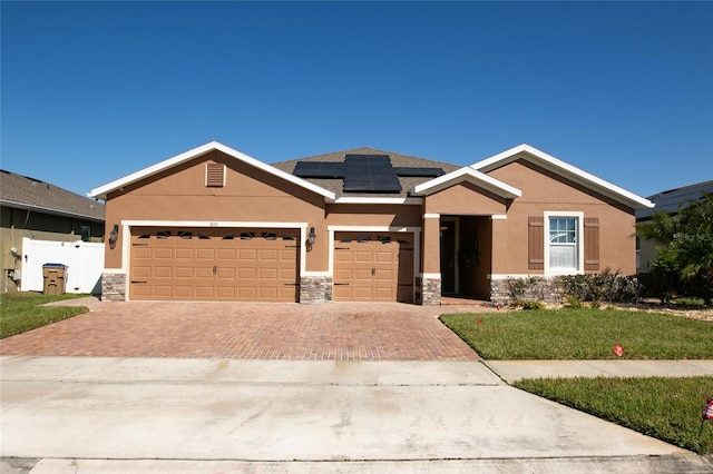 view of front of property featuring decorative driveway, stone siding, roof mounted solar panels, and stucco siding