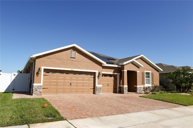 view of front of home with stone siding, stucco siding, decorative driveway, and a gate