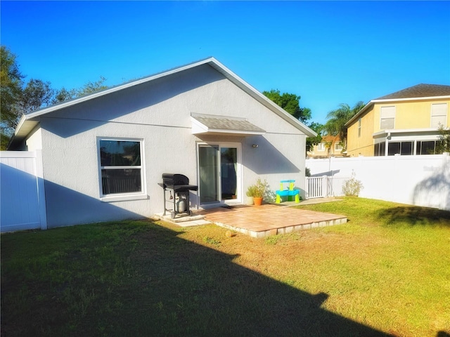 rear view of house featuring a patio area, a yard, fence, and stucco siding