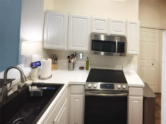 kitchen featuring white cabinetry, stainless steel appliances, a sink, and light countertops