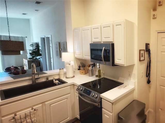 kitchen featuring stainless steel appliances, light countertops, visible vents, white cabinets, and a sink