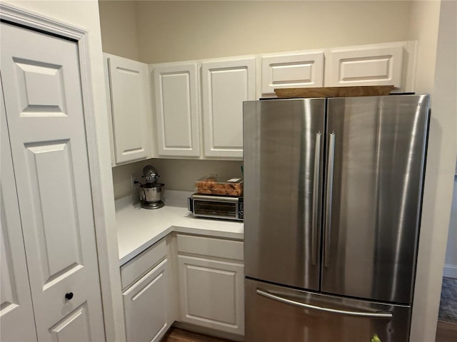 kitchen with light countertops, freestanding refrigerator, and white cabinetry