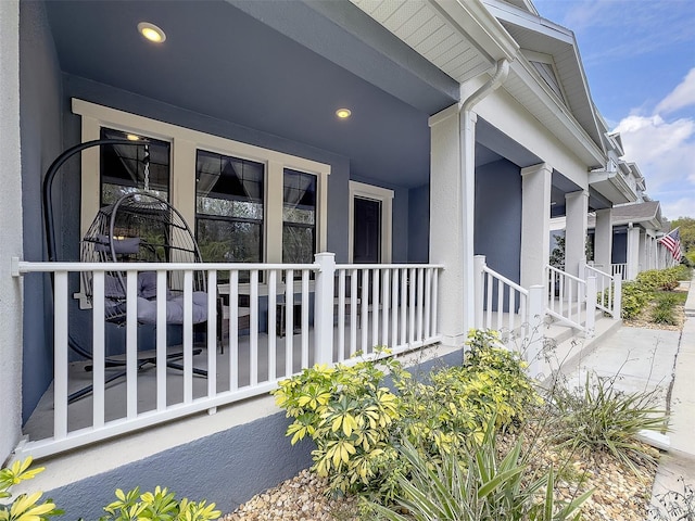 view of exterior entry with a porch and stucco siding