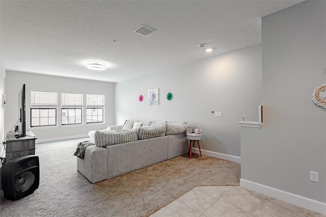 carpeted living room featuring a textured ceiling, tile patterned floors, visible vents, and baseboards